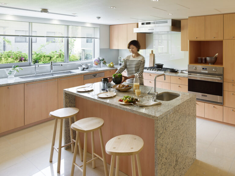 A lady cooking in a spacious kitchen with island counter