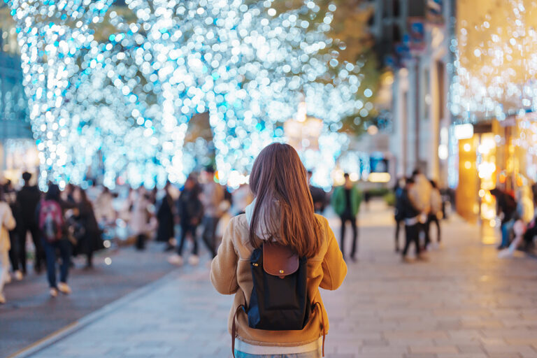 Traveler with bag visiting Roppongi Hills Christmas Illumination during winter season, happy tourist woman stands on a christmas market in Tokyo, Japan. Travel, holiday and celebrations concept