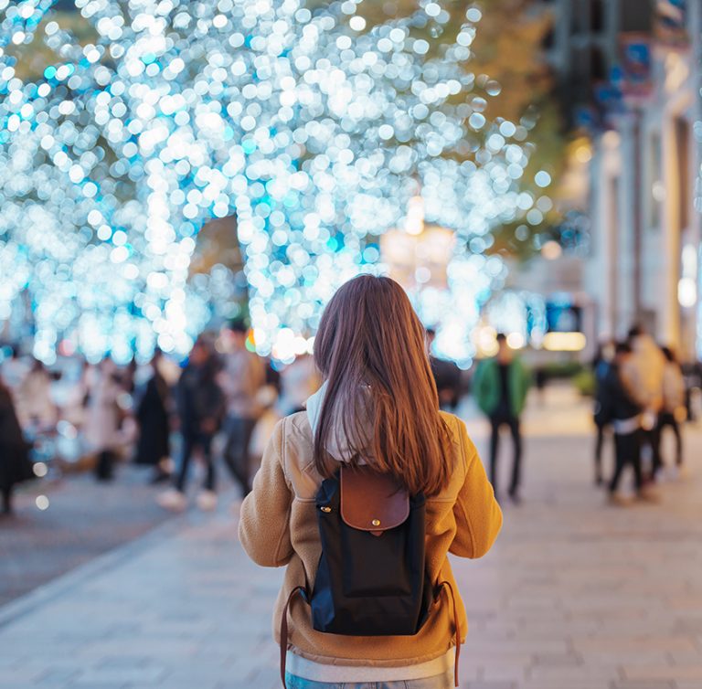 Traveler with bag visiting Roppongi Hills Christmas Illumination during winter season, happy tourist woman stands on a christmas market in Tokyo, Japan. Travel, holiday and celebrations concept